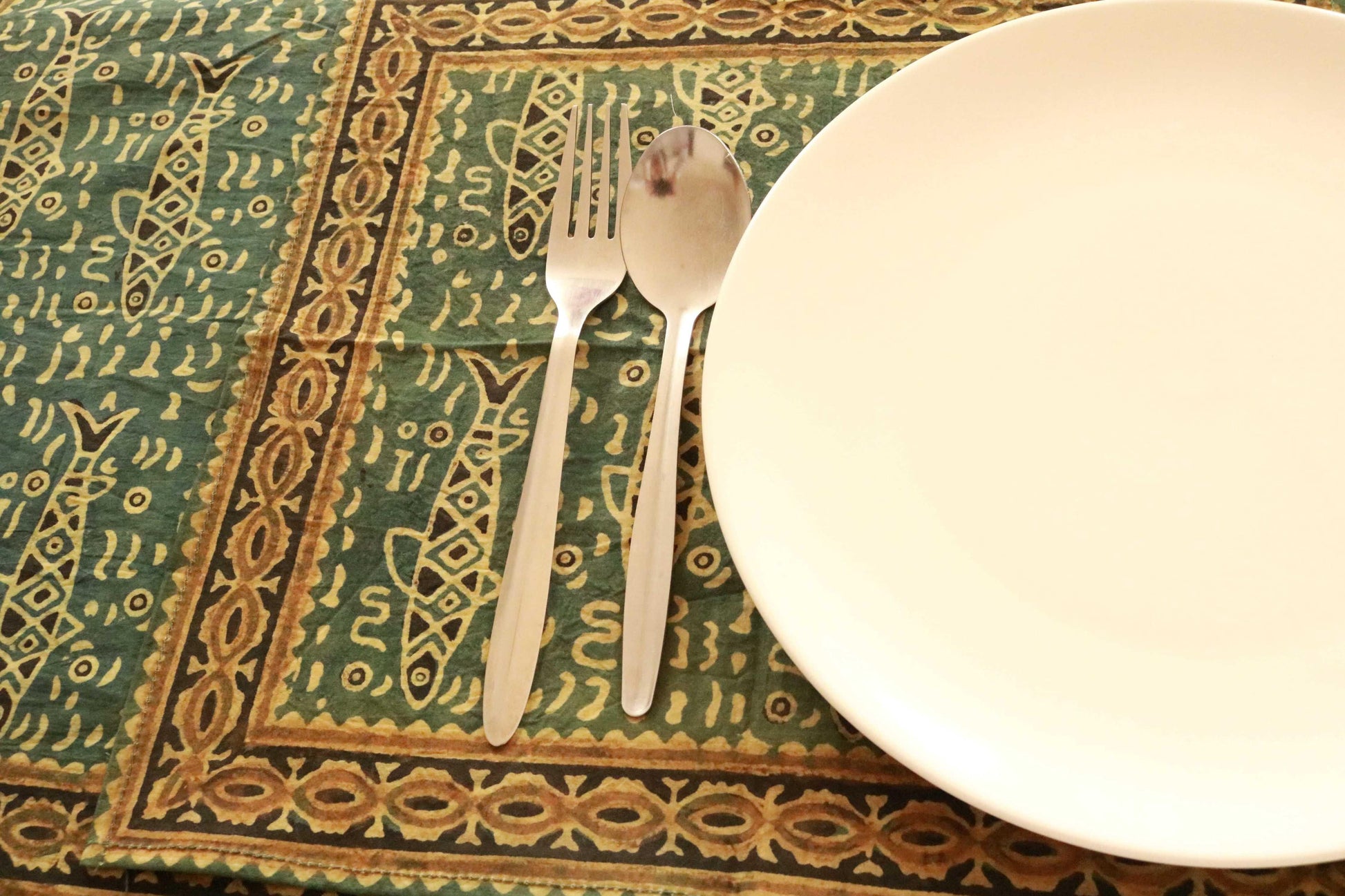 Green and saffron hand-dyed block print table cover with 8 matching napkins showcasing fish and floral patterns - an eco-friendly and ethically made dining ensemble by Ethimaart.