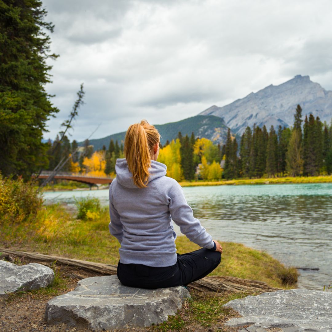boho girl meditating infront of mountains near sea 