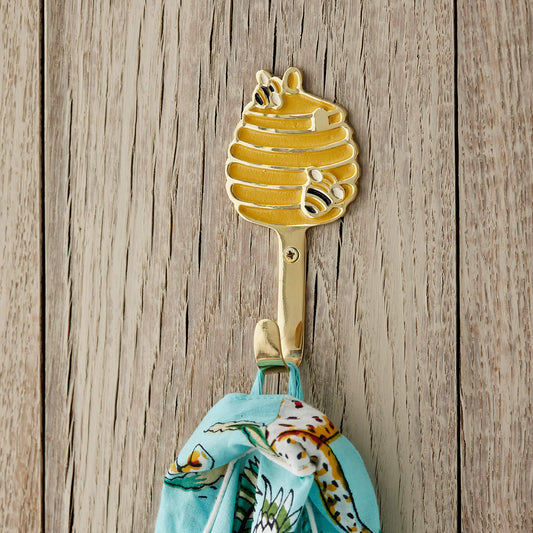 Gold honeycomb shaped hook with a colorful towel on a wooden background. beehive brass wall hook
