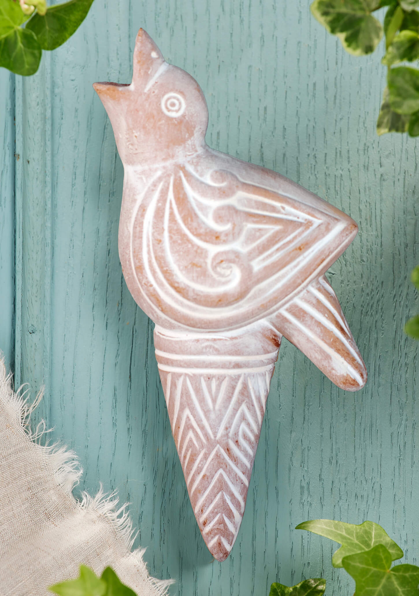 Handmade terracotta bird water spike in a sunny UK flower garden with blue hydrangeas