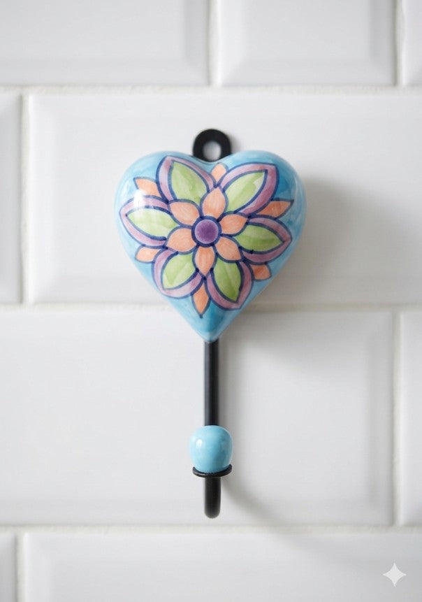 Heart-shaped ceramic hook with floral design on a white tiled wall