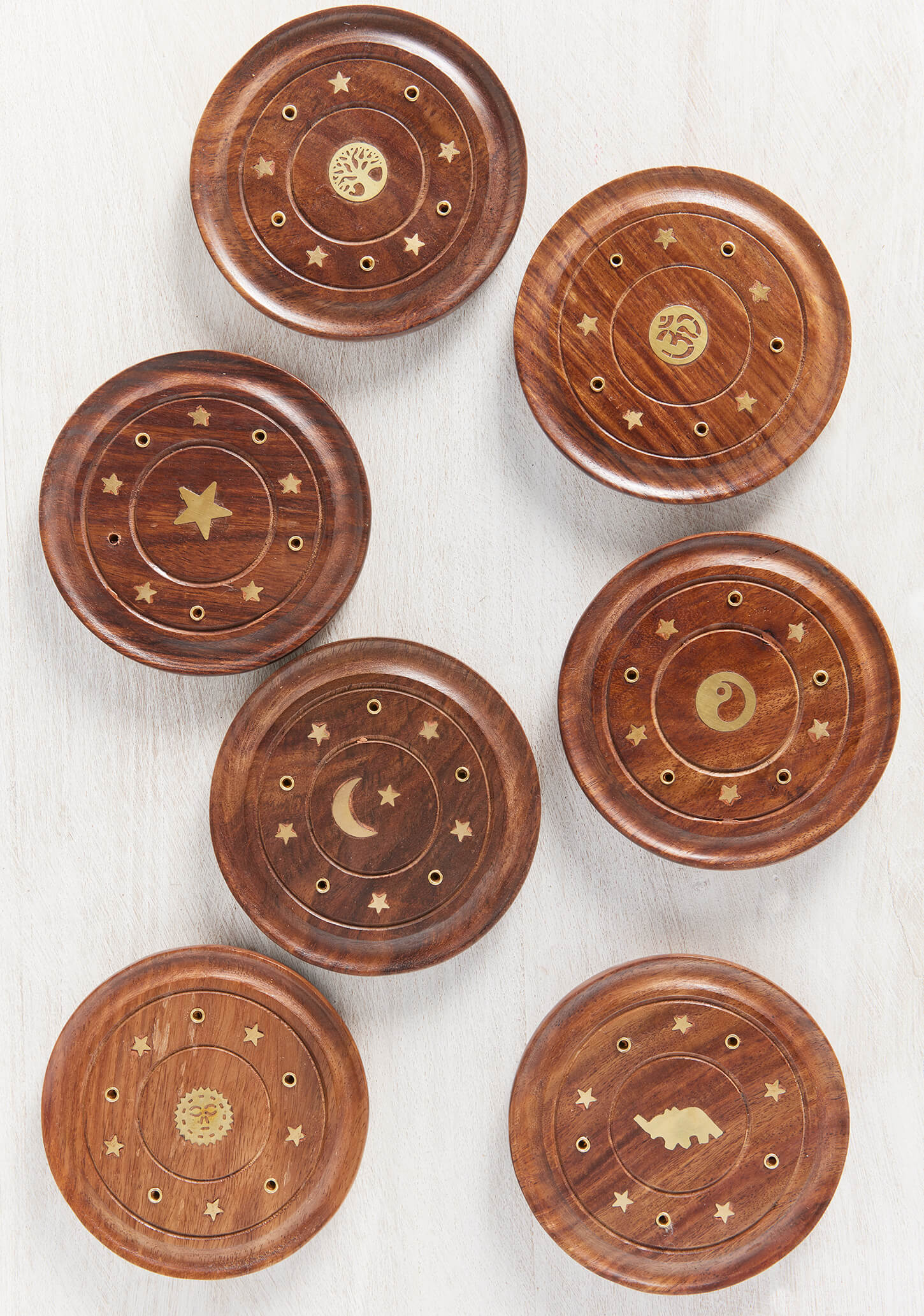 Close-up detail of a hand-crafted wooden incense plate featuring an intricate brass Om symbol inlay and decorative brass star accents.