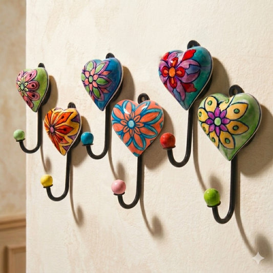 Colorful floral-patterned heart-shaped hooks on a beige wall.