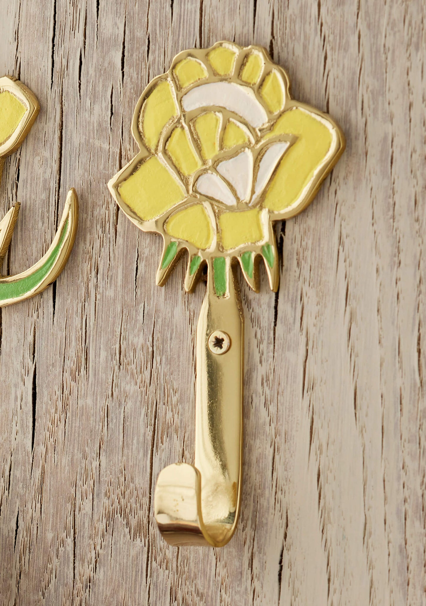 Decorative yellow flower wall hook on a wooden surface