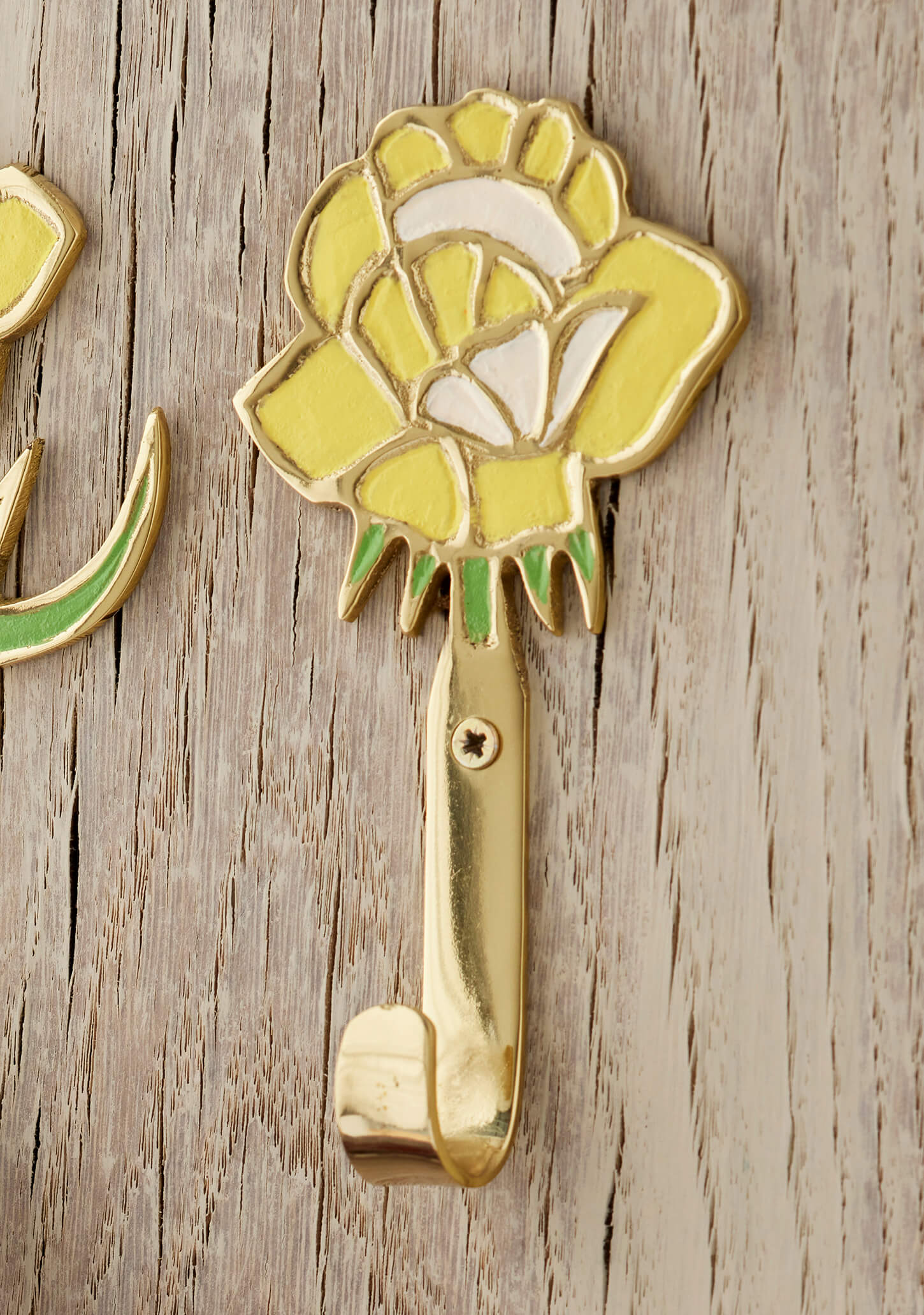 Decorative yellow flower wall hook on a wooden surface