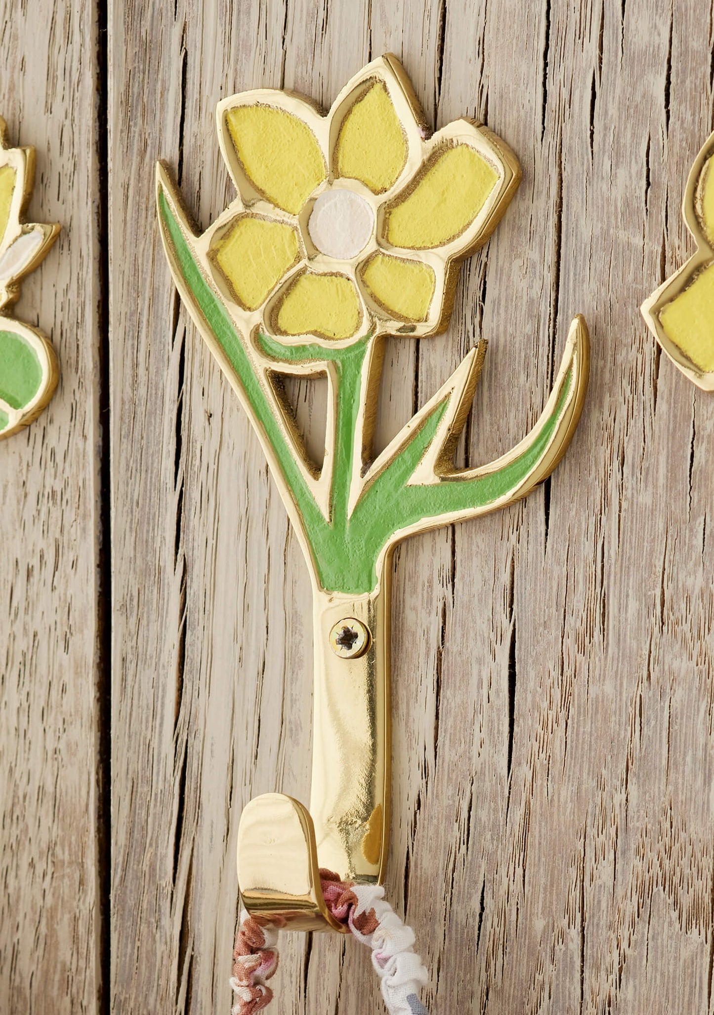 Decorative yellow flower wall hook shaped on a wooden surface